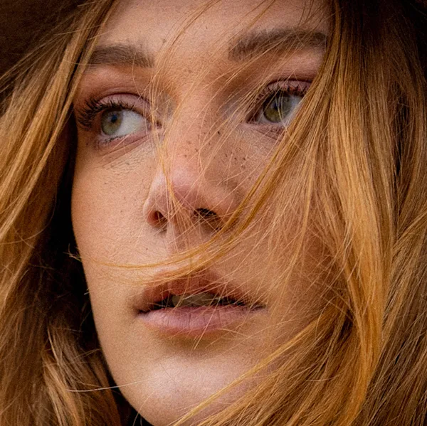 Woman with long, wavy, brown hair falling to the side.