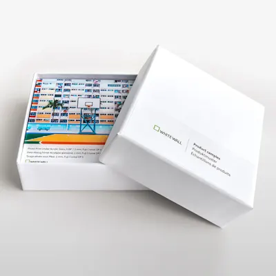 Shopify | Product Grid Section | Produktmuster Kachel Witte doos met open deksel toont kleurrijk bedrukte productmonsters van WhiteWall.