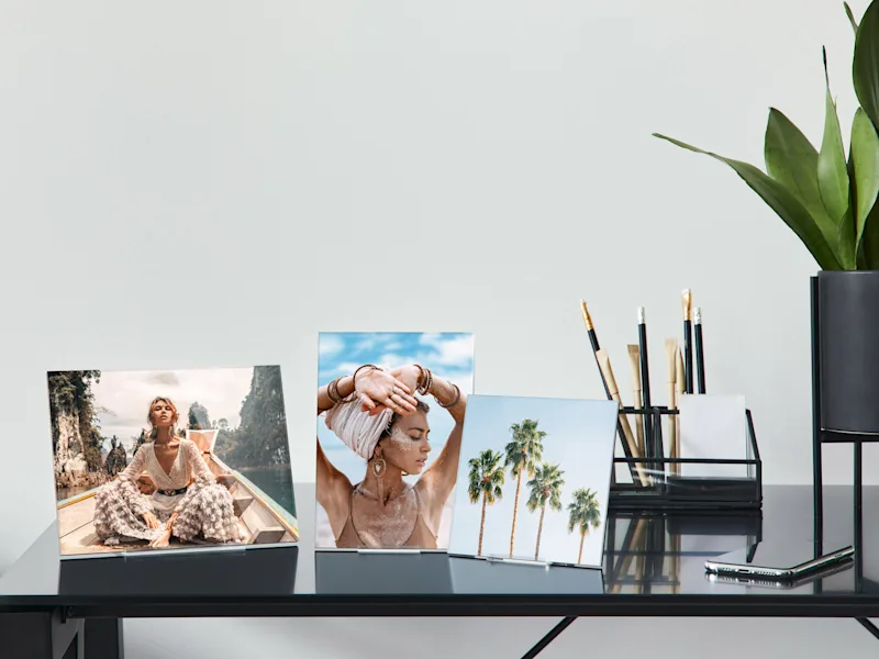 Fotoaufsteller aus Acrylglas Drei Fotoaufsteller aus Acrylglas mit verschiedenen Fotos: Person auf Boot, Person mit erhobenen Armen, Gruppe von Palmen.de