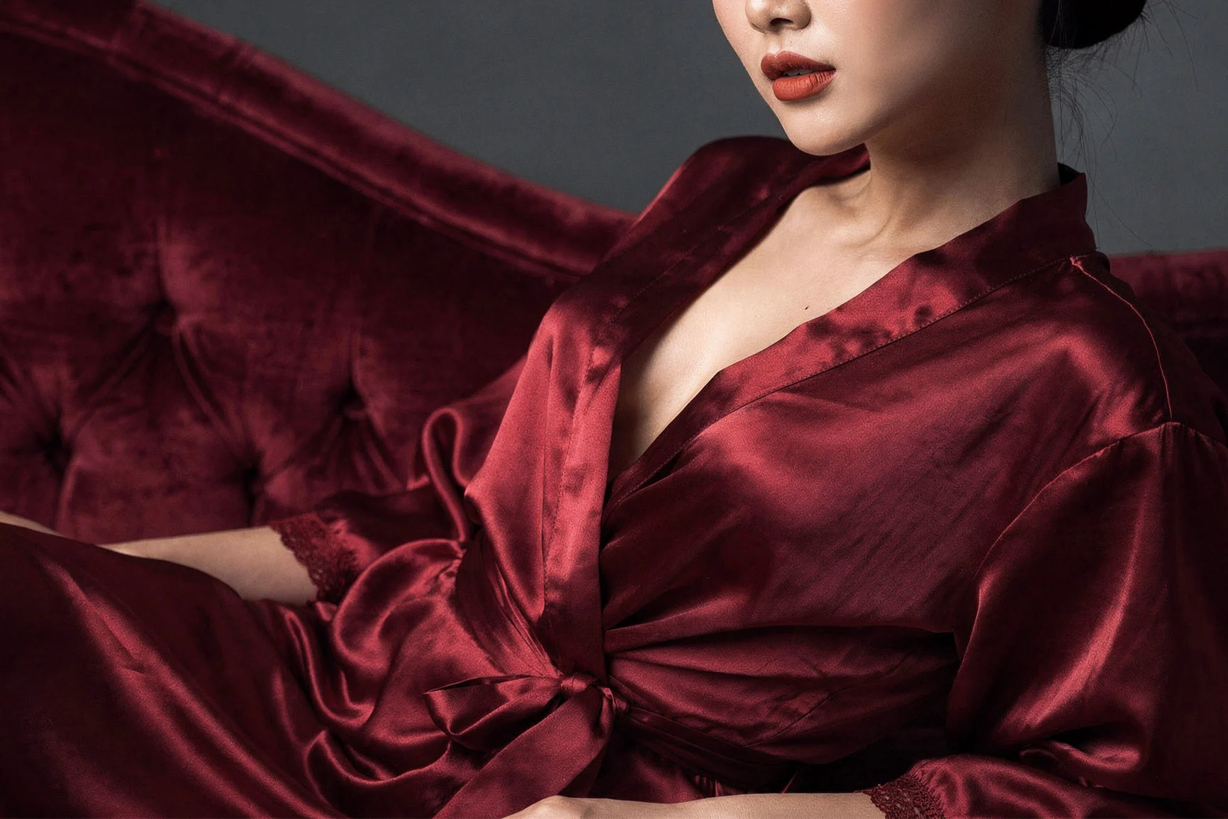 Woman in a red silk kimono Frau in rotem Seidenkimono mit offenem Kragen vor dunklem Hintergrund.