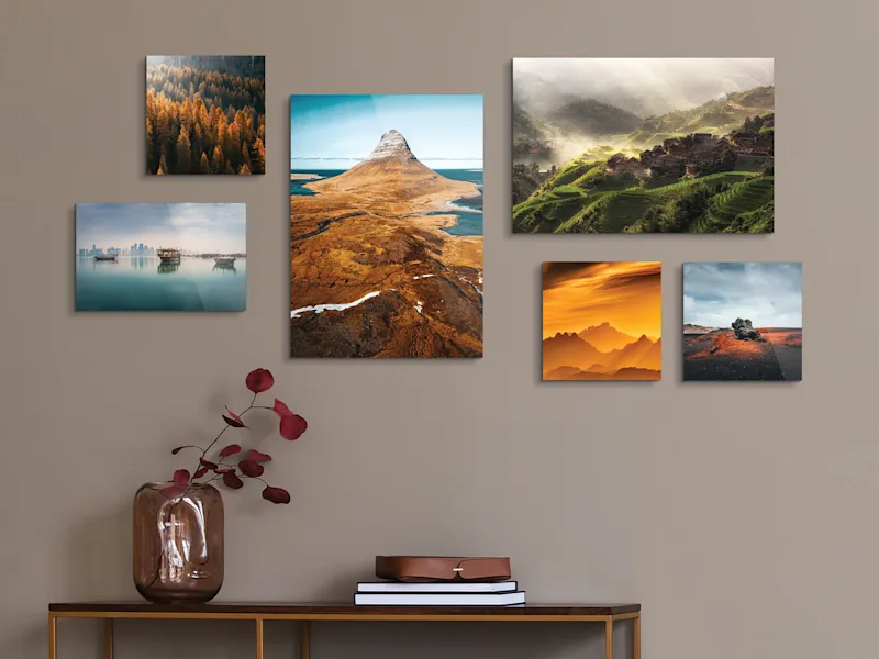 Foto-Abzug auf Holz Sechs Fotoabzüge auf Holz mit Landschaftsmotiven in verschiedenen Formaten an einer Wand über einem Tisch.