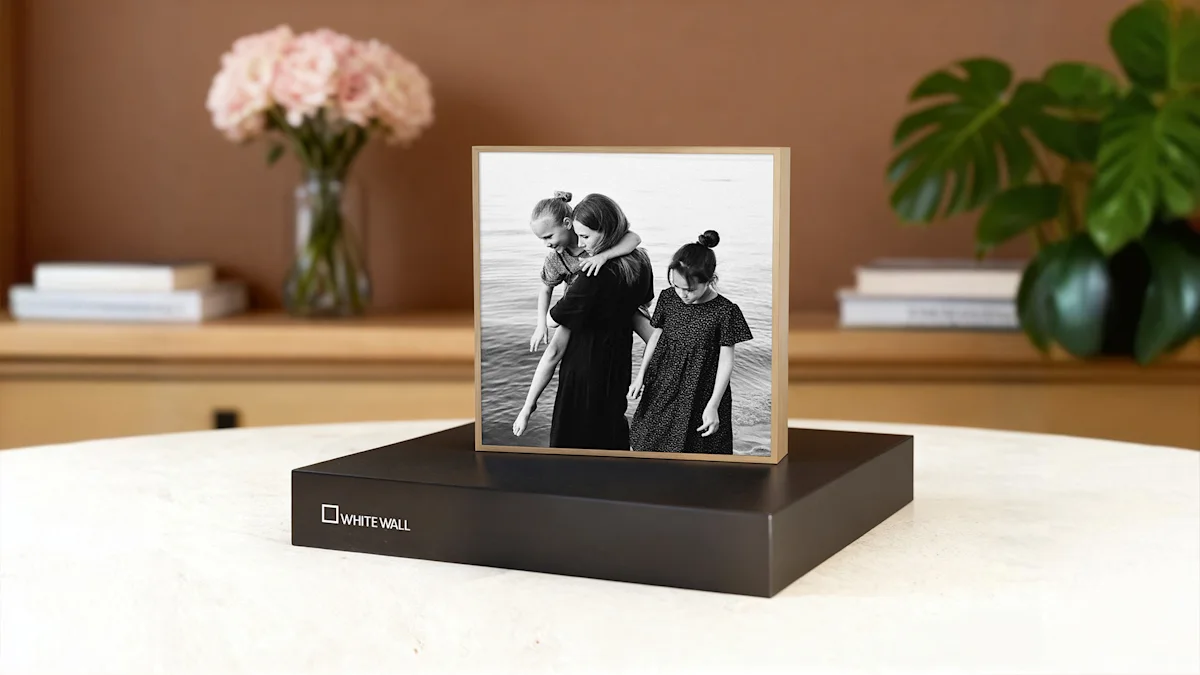 artbox gift edition standing on a table Black and white family photo displayed in a modern standing frame with gift box, with pink flowers and greenery in background.
