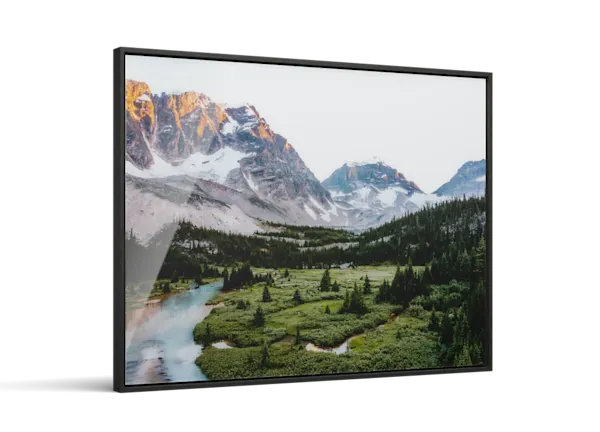 Framed landscape print showing snow-capped mountains, a winding blue river, and lush green forest valley under a misty sky.