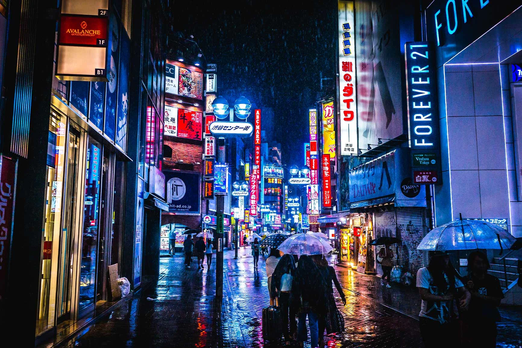 Street at night with neon signs A nighttime shot of a busy street in the rain, lit by numerous colorful neon signs.