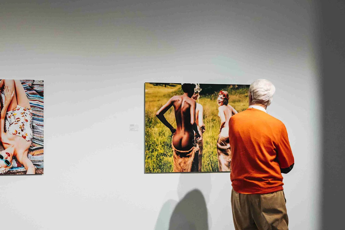 Un homme regarde deux photographies Un homme regarde deux photographies accrochées à un mur blanc dans une galerie, toutes deux représentant des femmes sous différents angles.