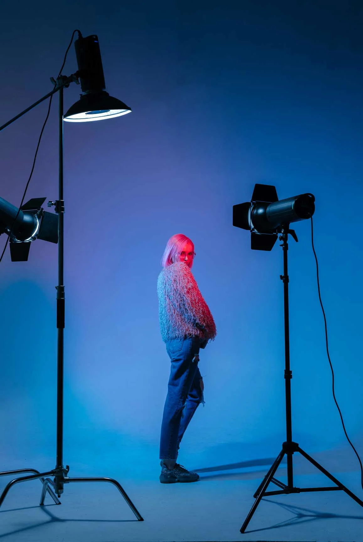 Een persoon staat in een fotostudio met blauwe achtergrondverlichting. Een persoon staat in een fotostudio met blauwe achtergrondverlichting.
