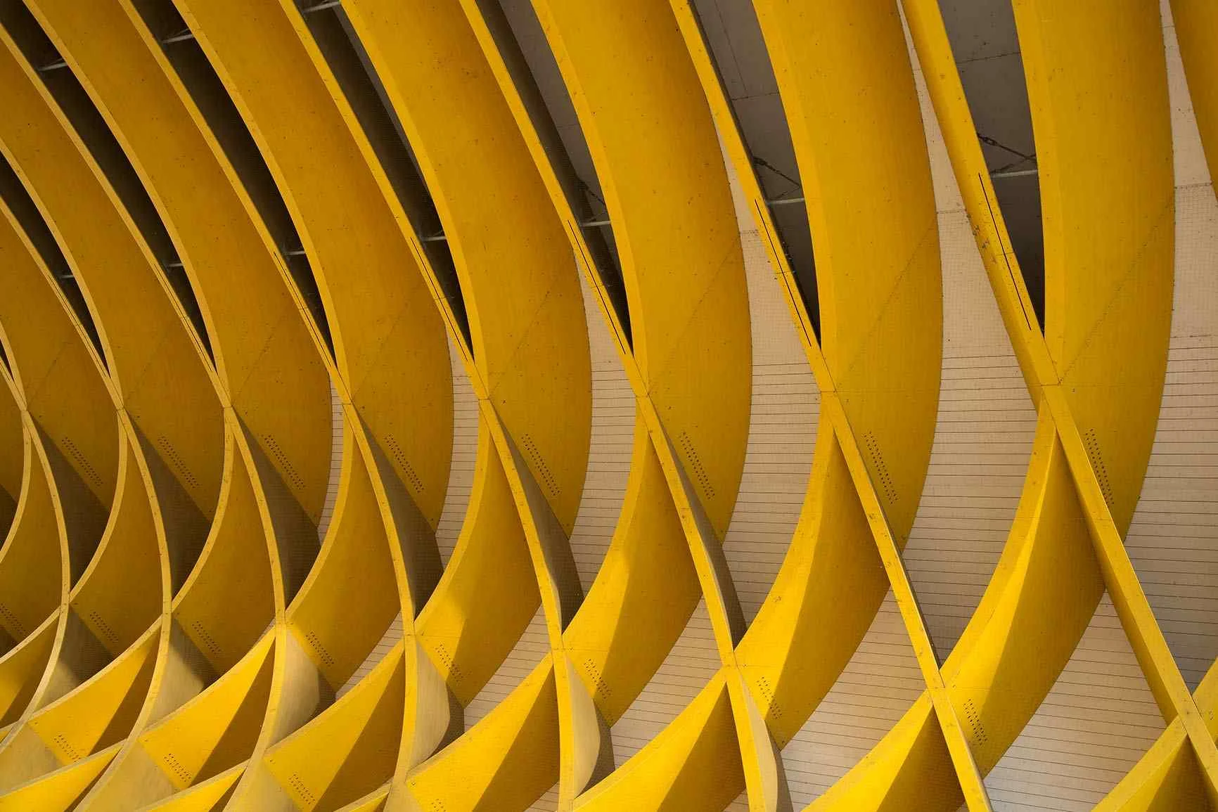Abstract yellow architectural pattern An abstract architectural photograph featuring recurring, curved yellow elements against a light background.