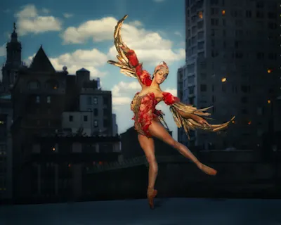 Couleurs & contrastes 1 Misty Copeland danse sur un toit devant une ligne d'horizon nocturne, vêtue d'un costume rouge aux ailes dorées.