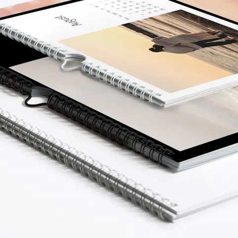 Calendari WhiteWall in vari design Tre calendari fotografici con rilegatura a spirale impilati su una superficie bianca