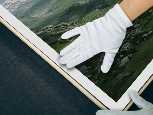 Professionelles Fotolabor Draufsicht auf gerahmte Wandkunst mit einer behandschuhten Hand, die den Druck vorsichtig berührt