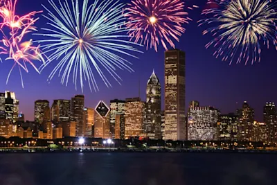 Feuerwerksfotografie Feuerwerk über beleuchteter Skyline bei Nacht mit bunten Lichtern am Himmel.