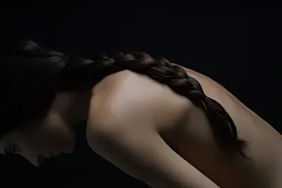 Close-up of a woman from the side A close-up shot from the side of a woman with a braided strand of hair falling down her back.