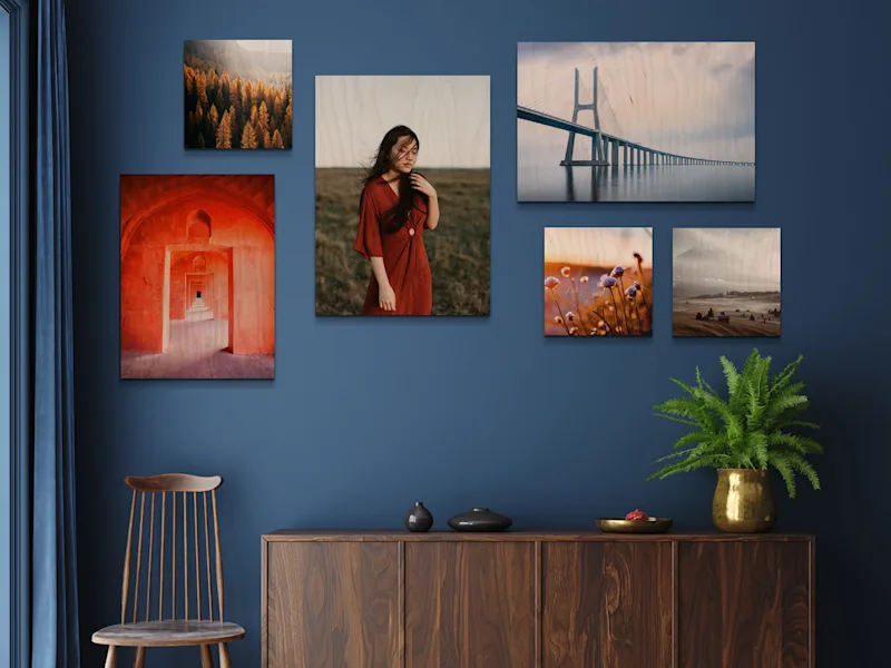 Direct Print On Wood Several photo prints on wood in various formats on a blue wall, including landscapes, flowers, and a person in a red dress.