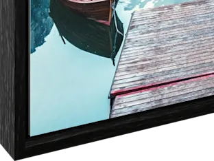 Stampa fotografica sotto vetro acrilico con cornice flottante Angolo di una cornice in legno con scanalatura che mostra parte di un'immagine con una barca e un molo sull'acqua.