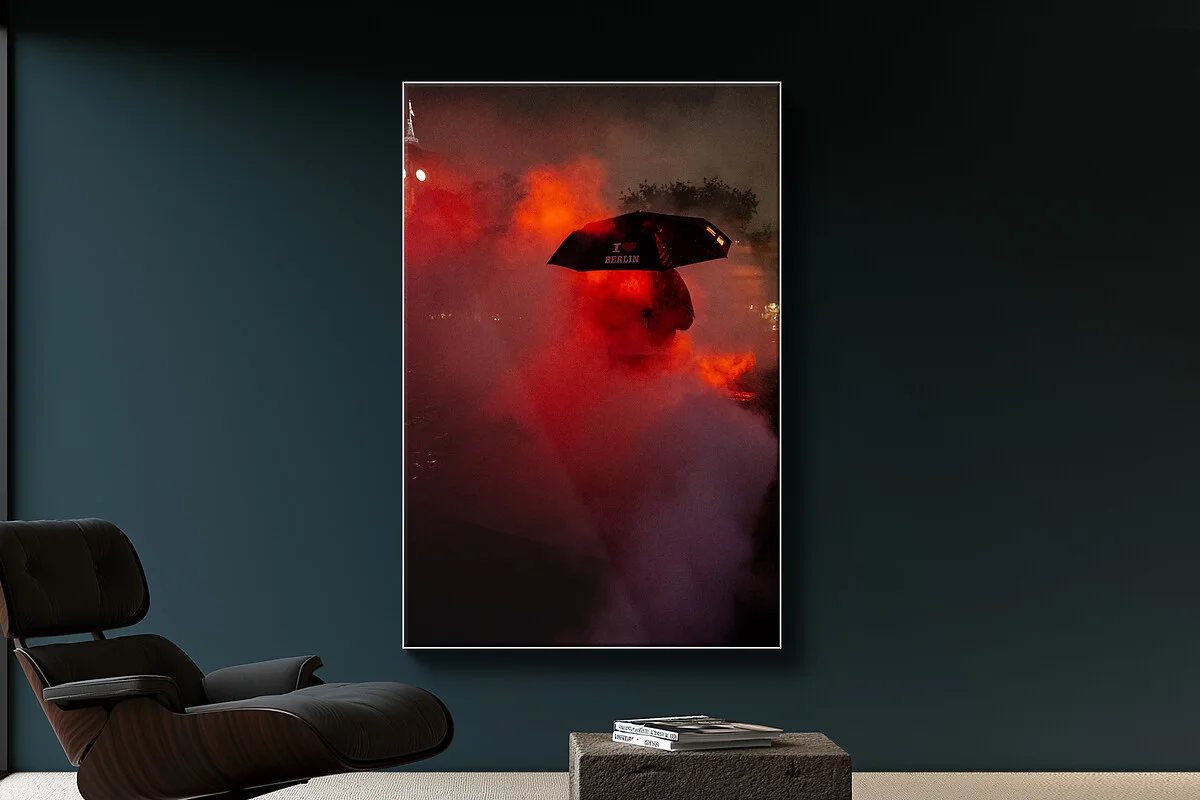 Slimline Rahmen mit Bild einer Person, die bei Nebel und rotem Licht einen Regenschirm hält, an dunkelblauer Wand. Slimline Rahmen mit Bild einer Person, die bei Nebel und rotem Licht einen Regenschirm hält, an dunkelblauer Wand.