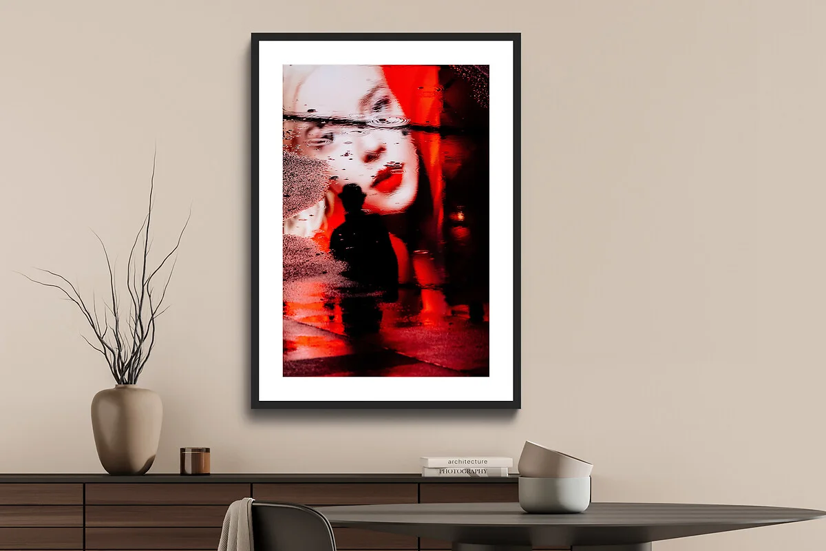 Passepartout-Rahmen mit einem rot dominierenden Bild, das eine Person und eine Straße zeigt, an einer beigen Wand. Passepartout-Rahmen mit einem rot dominierenden Bild, das eine Person und eine Straße zeigt, an einer beigen Wand.