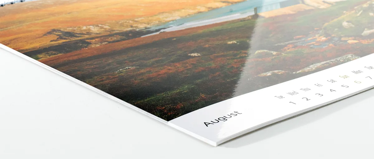 Photo Calendar Photo paper glossy Close-up view of a calendar page showing August, with a glossy printed landscape image visible at an angle