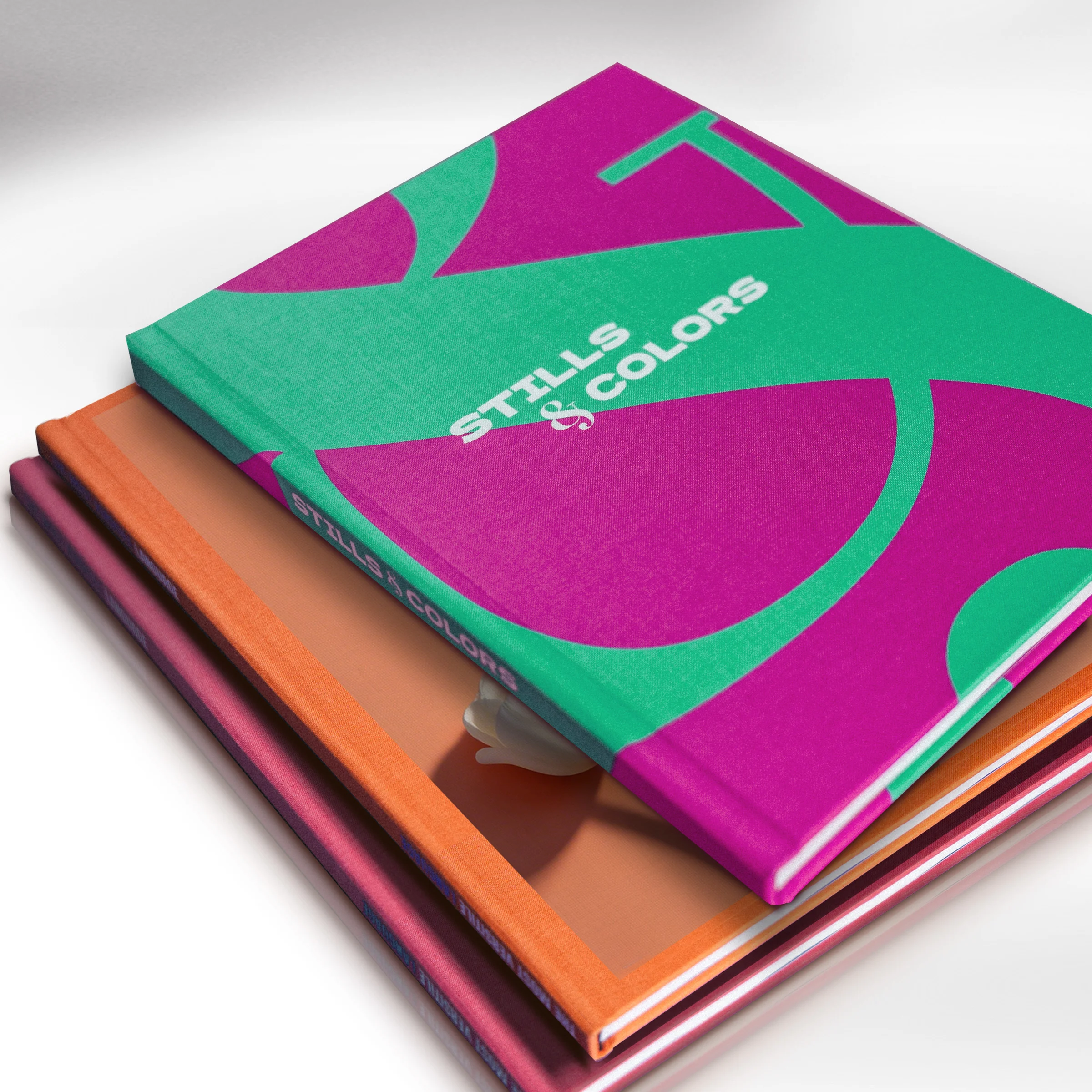 Coffee Table Books with colorful covers Three Coffee Table Books with colorful covers are stacked on top of one another; on top is a book titled ‘STILLS & COLORS’ in white lettering on a green-and-purple background.