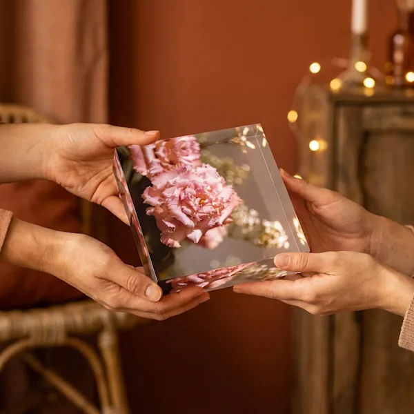 Acrylic photo block as a gift Hands giving an acrylic photo block of pink carnations as a gift.