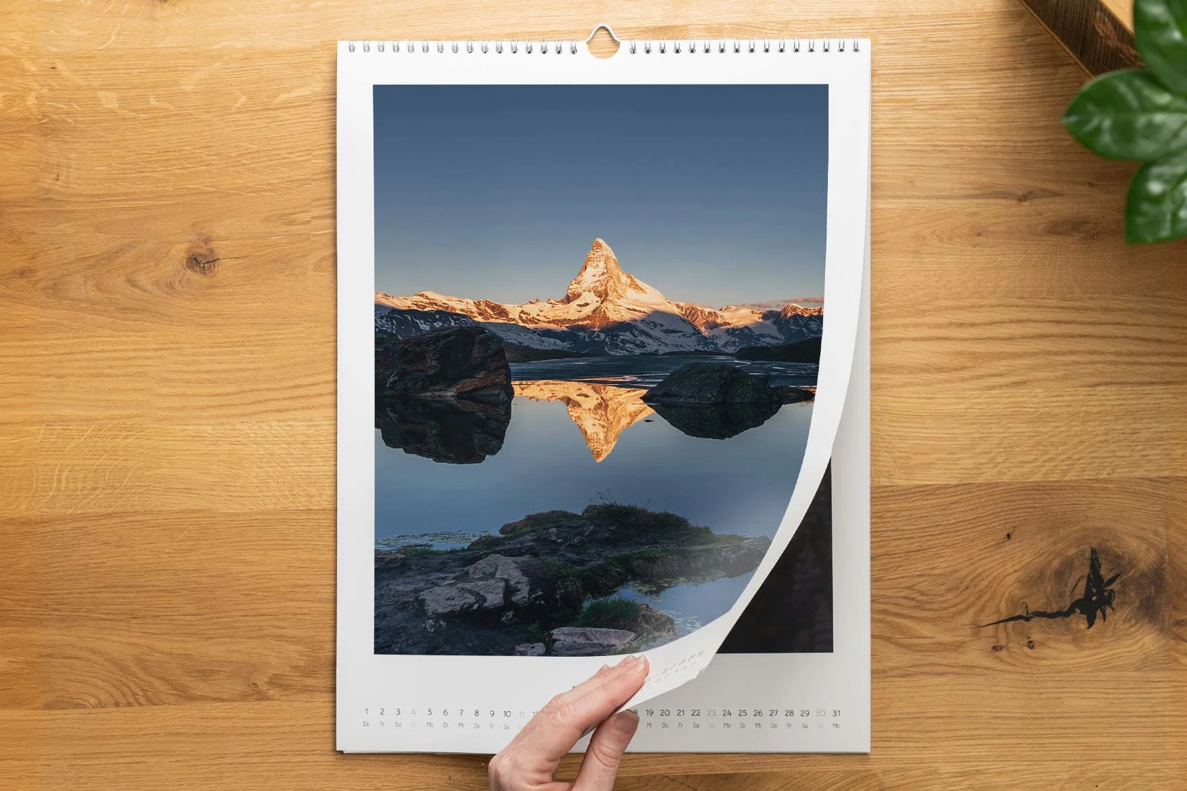 Photo calendar shows the Matterhorn reflected in a lake, hand turning to the next page. Photo calendar shows the Matterhorn reflected in a lake, hand turning to the next page.
