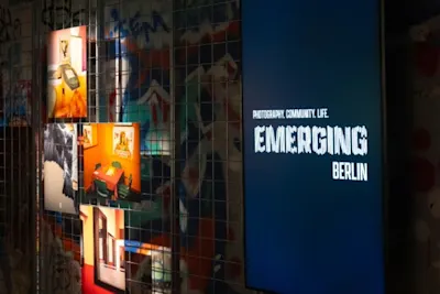 Emerging Berlin exhibition Luminous photo exhibition with the lettering “EMERGING BERLIN” on a lattice wall with graffiti.