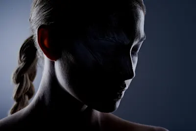 Portrait of a woman with her hair braided to the side Portrait of a woman with her hair braided to the side, against a dark background with side lighting.