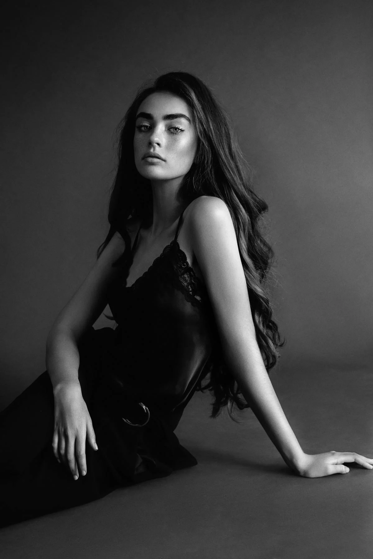 Woman with long, wavy hair sitting on the floor, wearing a sleeveless black dress in black and white. Woman with long, wavy hair sitting on the floor, wearing a sleeveless black dress in black and white.