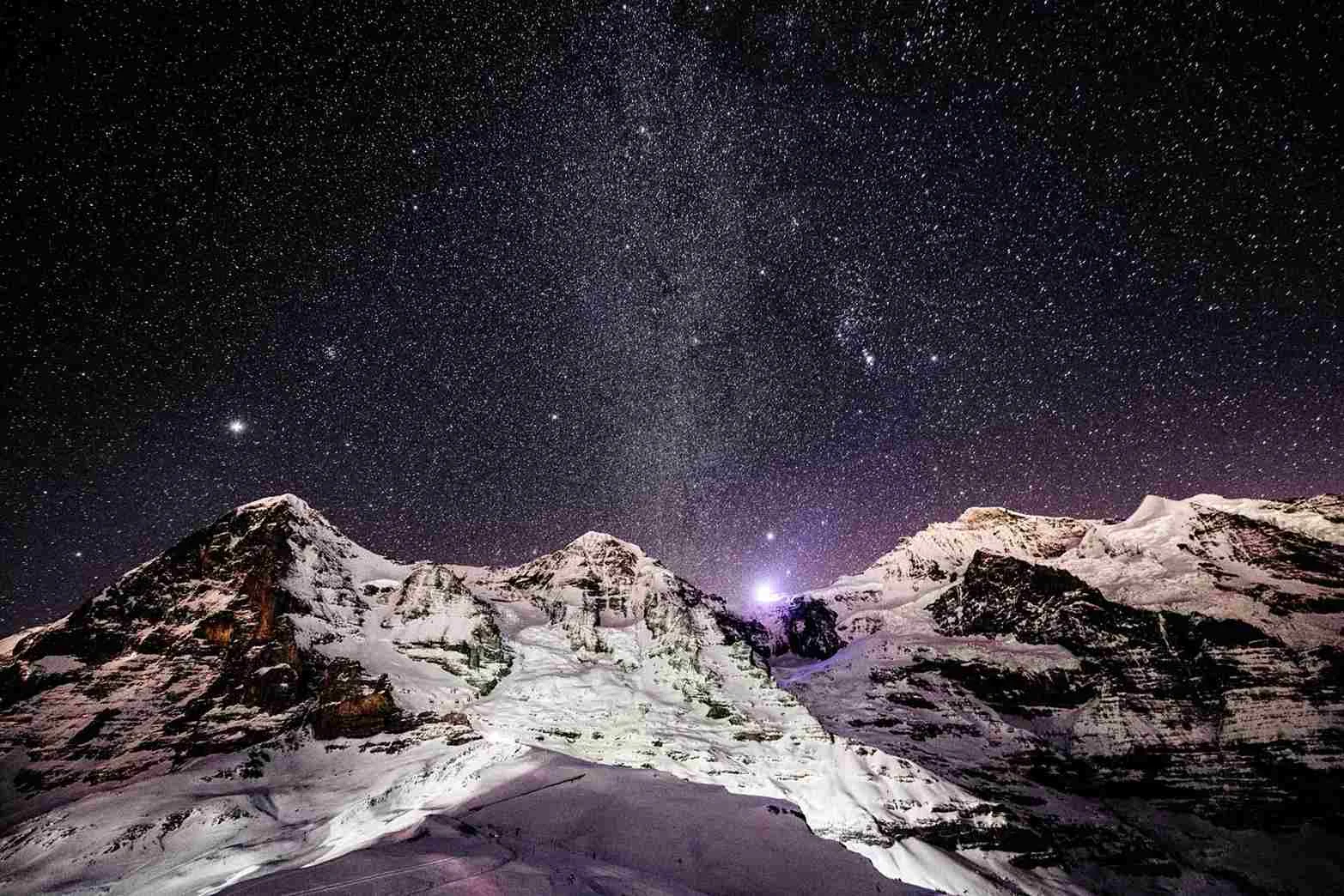 Mountain peaks under a starry sky Snow-capped mountain peaks beneath a clear starry sky with the Milky Way visible.