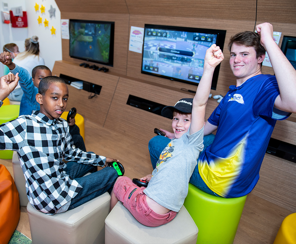 Male volunteer in the Starlight Express Room playing video games with kids