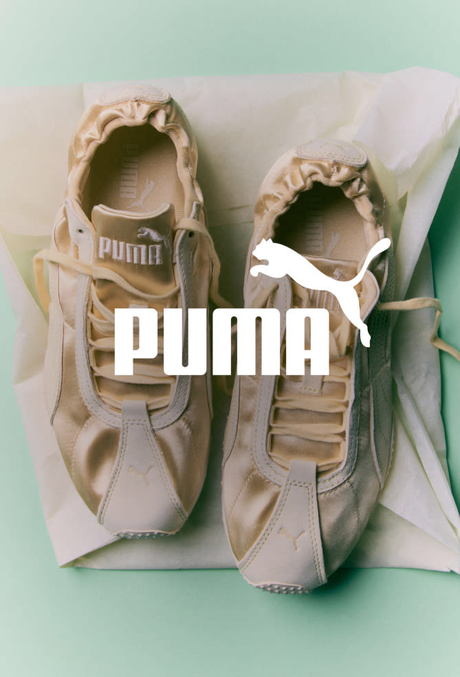 Pair of beige Puma sneakers with white Puma logo and leaping cat emblem on tissue paper against mint green background.