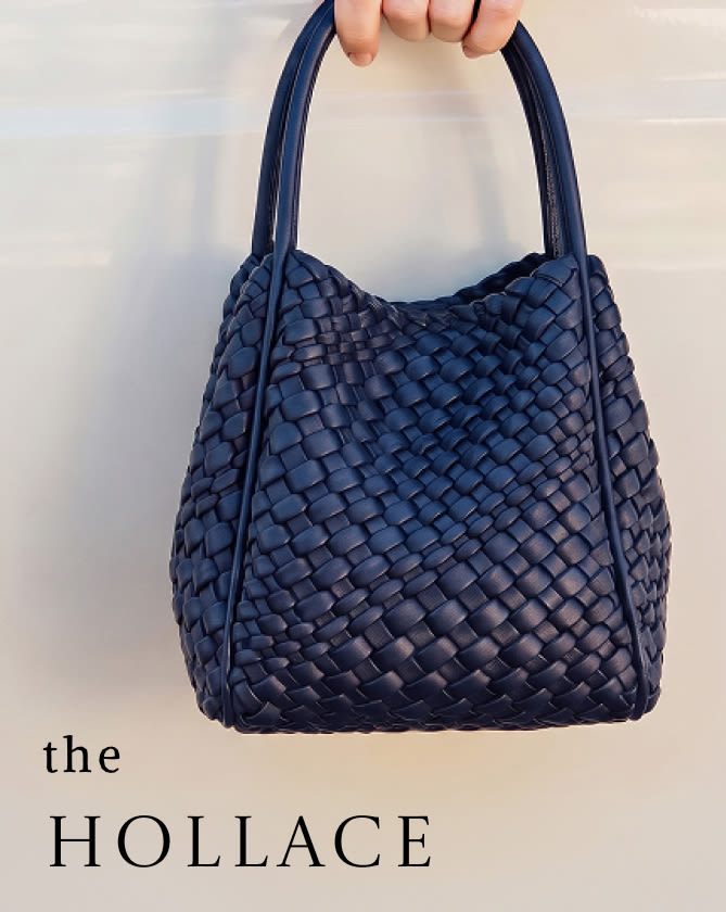 Hand holding a navy blue woven leather handbag with text "the HOLLACE" on light background