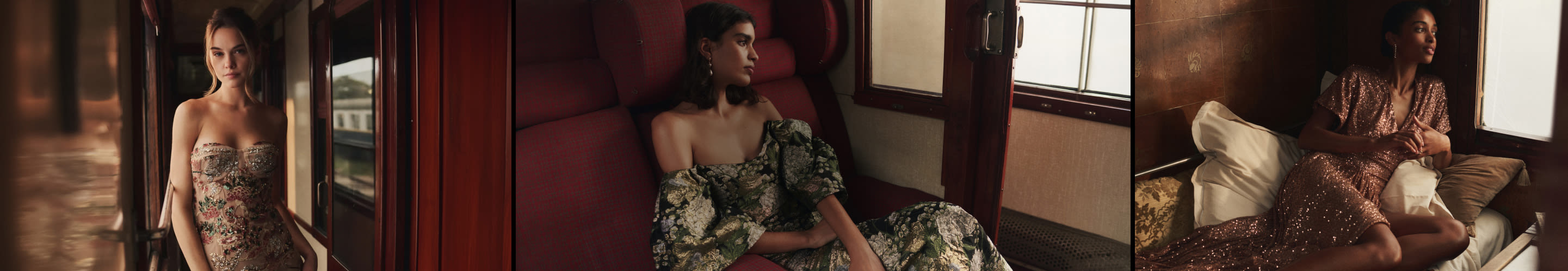 Three models in elegant evening gowns pose in a vintage train car with wood paneling and windows.