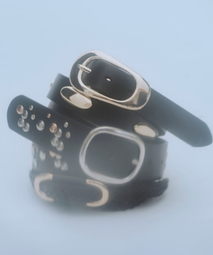 Three black leather belts with silver buckles stacked together on a light blue background.