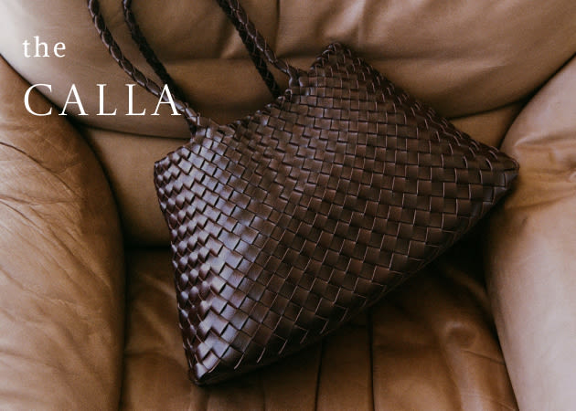 Brown woven leather handbag with braided handles on tan leather couch with text the CALLA in white letters