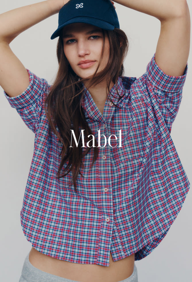 Woman wearing navy baseball cap and red, white, and blue plaid shirt with text overlay reading Mabel