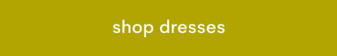 White text reading 'shop dresses' centered on a mustard yellow rectangular button background