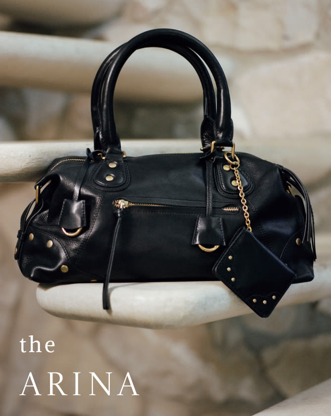Black leather handbag with gold hardware and chain detail displayed on white surface with text "the ARINA" in lower left corner.