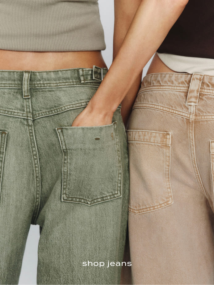 Two people standing side by side wearing olive green and beige jeans with visible back pockets. Text reads "shop jeans"