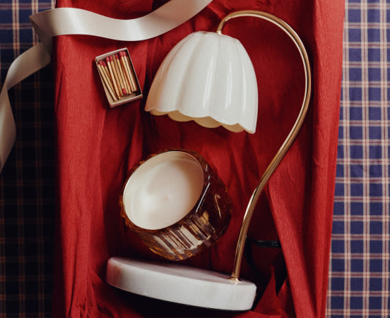 Vintage brass desk lamp with white glass shades on red fabric backdrop with blue plaid wallpaper and white ribbon accent.