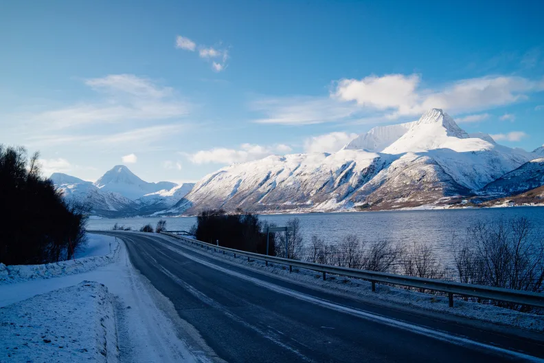 Blick von der Straße auf den See und die Berge.