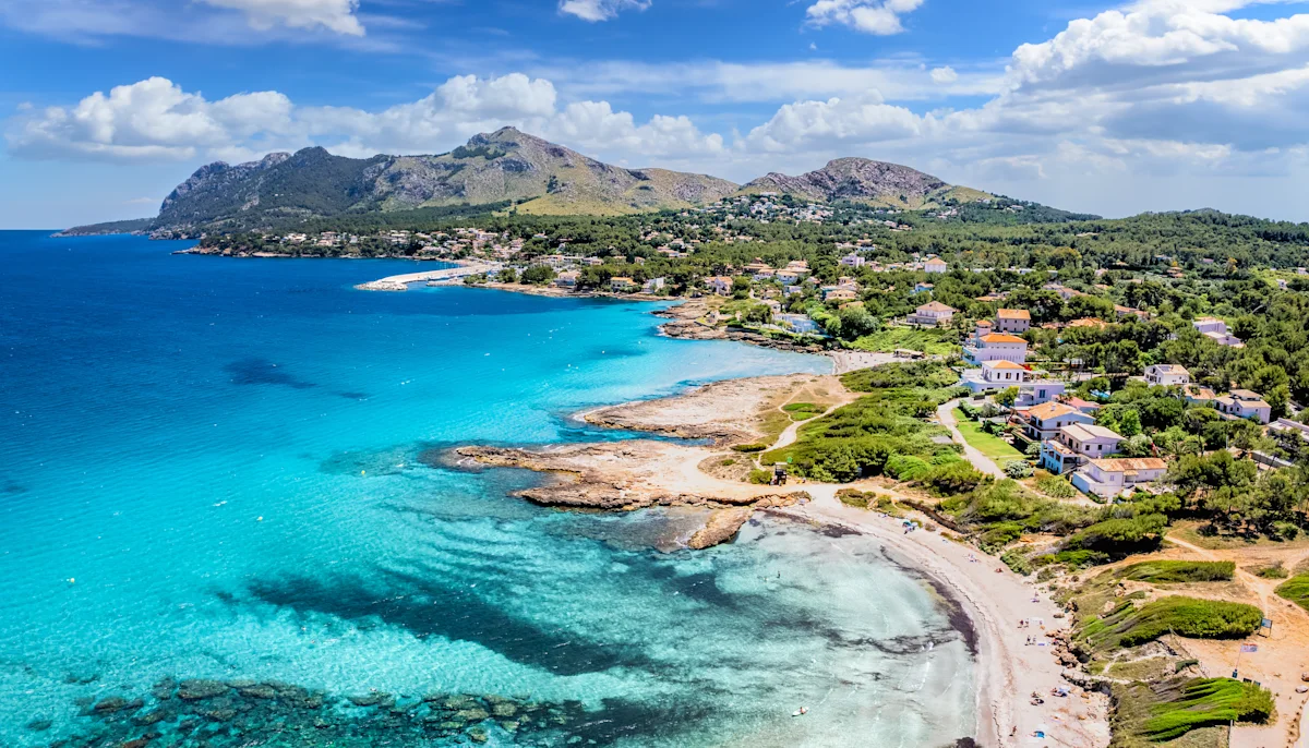 Blick auf eine Bucht in Alcudia, Mallorca mit türkisem Wasser und felsiger Küste.