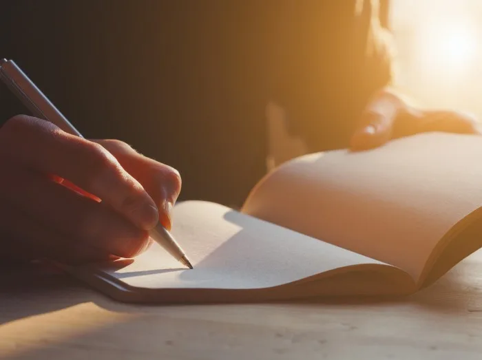 female hands writing notes on notebook with pen
