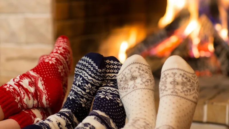 Feet in wool socks near fireplace in winter time