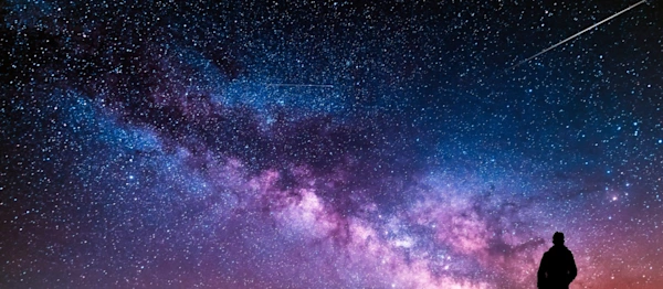 Beautiful starry night, man silhouette with a camera looking at the Milky Way galaxy.