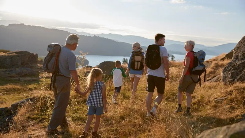 Rear View Of Multi Generation Family Walking On Top Of Hill On Hike Through Countryside In Lake District UK