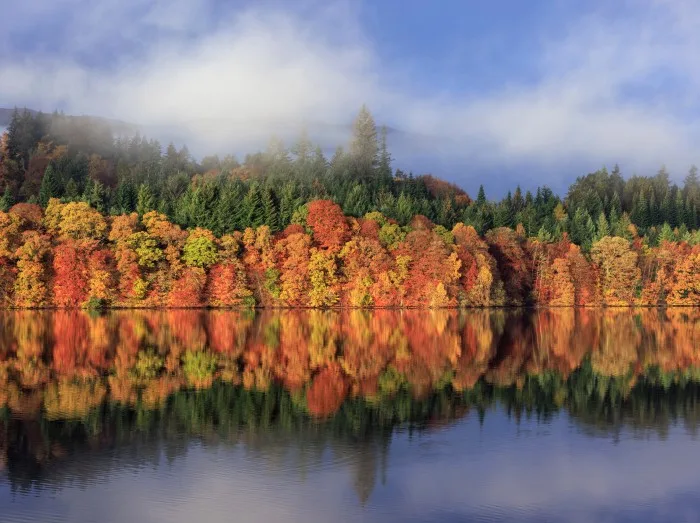 Picturesque Autumn Scene at Loch Faskally, Pitlochry, Perthshire, Scotland, Featuring Rich Fall Colors, Evergreen Forests, and a Stunning Water Reflection with Mist Rolling Over Distant