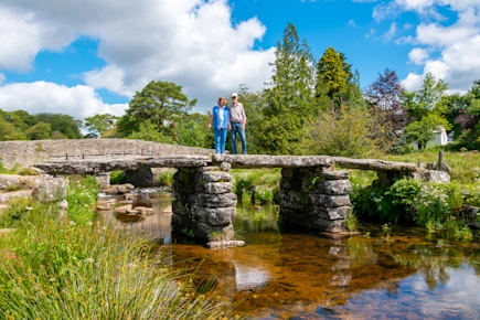 Couple standing on ancient clapper bridge at Postbridge, Dartmoor National Park, Devon, England
