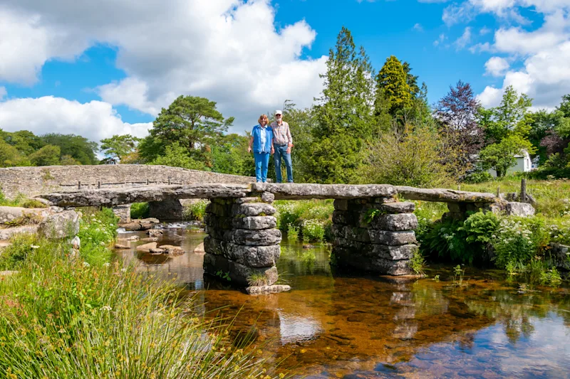 Couple standing on ancient clapper bridge at Postbridge, Dartmoor National Park, Devon, England