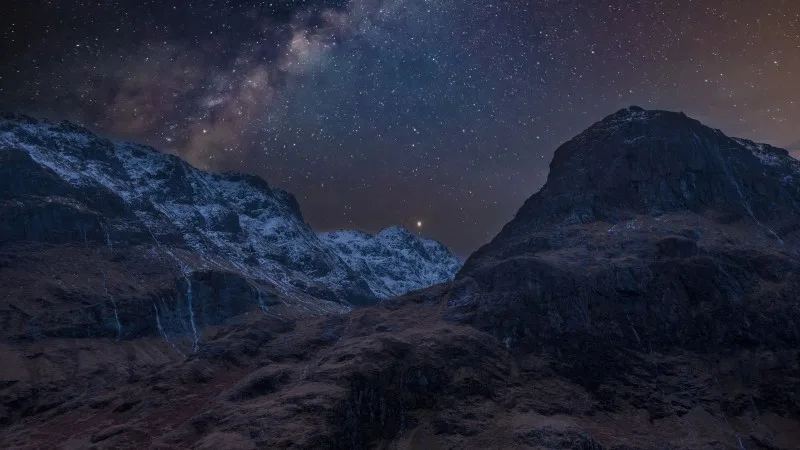 Majestic vibrant Milky Way composite image over landscape of snowcapped mountains in Scottish Highlands
