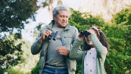 A child and adult birdwatching with binoculars in the countryside